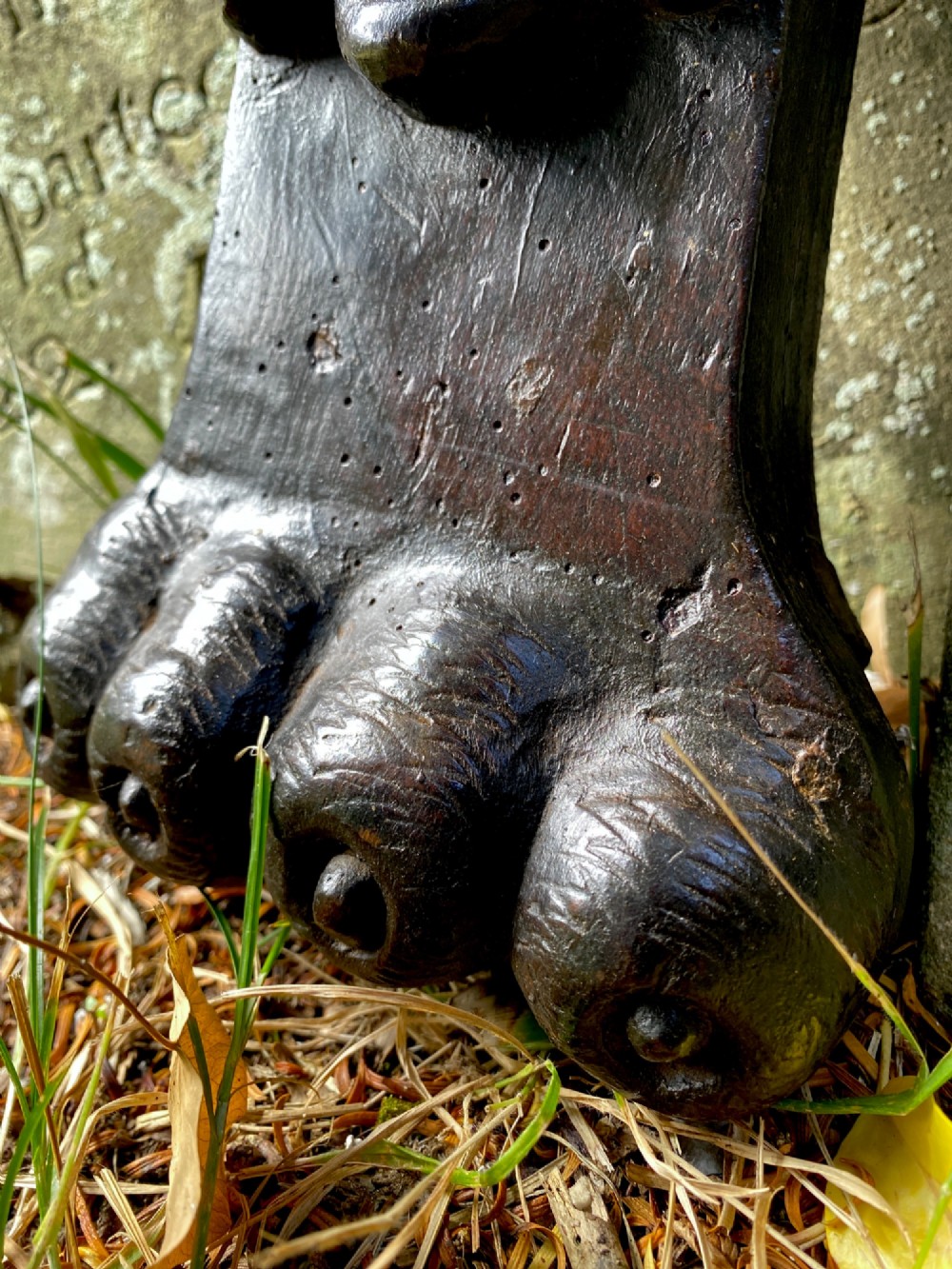 A hand-carved dark oak wood element featuring a stylised Green Man face tapering down into a lion paw base. View VI