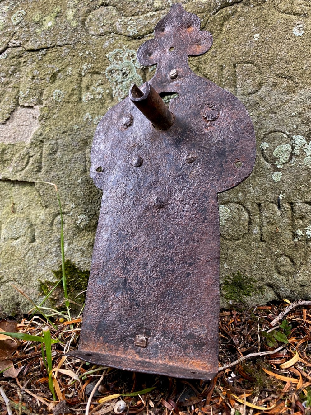 A hand-forged dark wrought iron lock plate featuring a trefoil crest, projecting key pipe, and surface oxidisation.