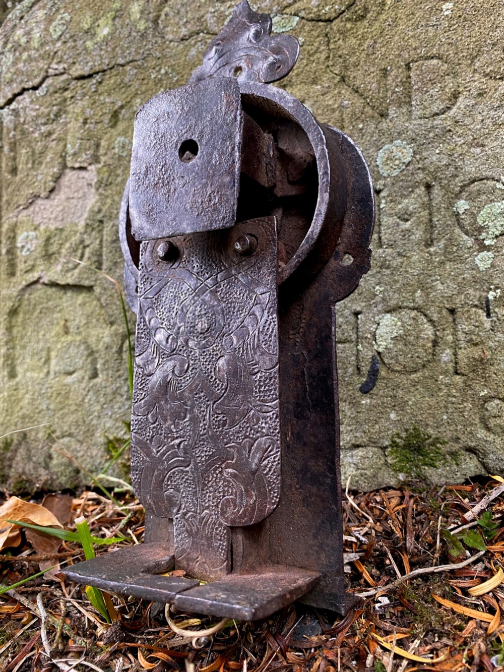 A hand-forged dark wrought iron lock plate featuring a trefoil crest, projecting key pipe, and surface oxidisation. View VII