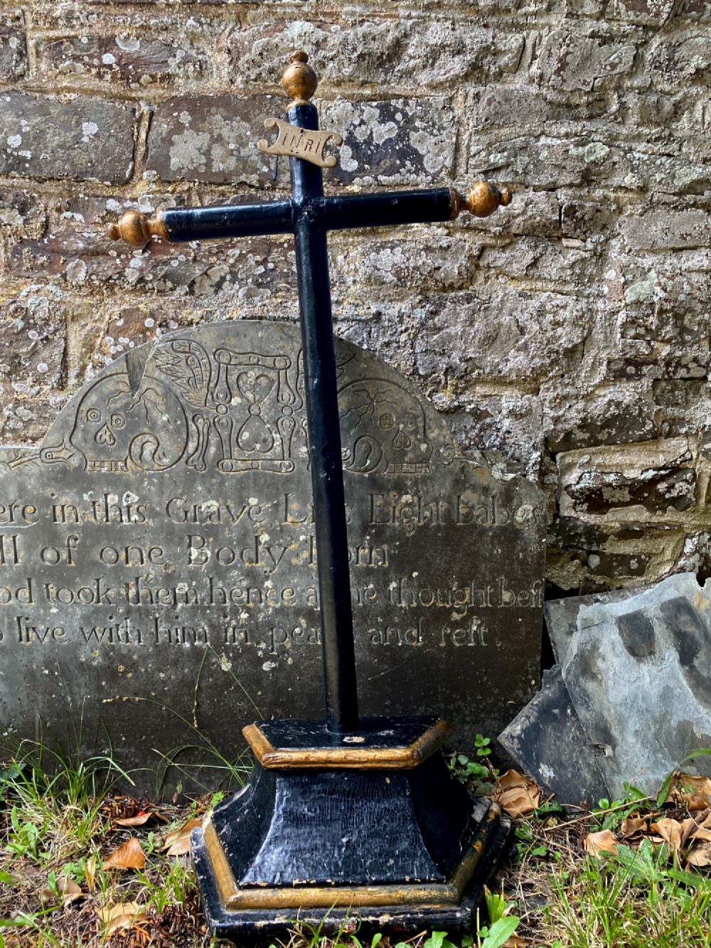 An 18th-century ebonised wooden cross with giltwood finials and an INRI scroll set upon a mould-shaped stepped base.