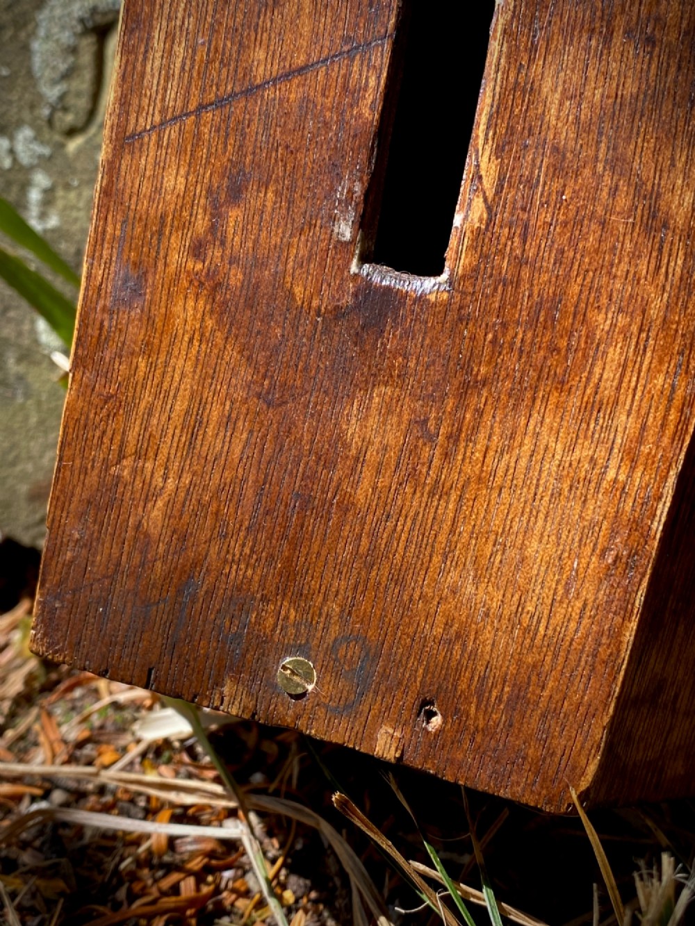 A wooden coffin-shaped collection box featuring a raised wooden cross motif and a narrow coin slot on the front lid. View III