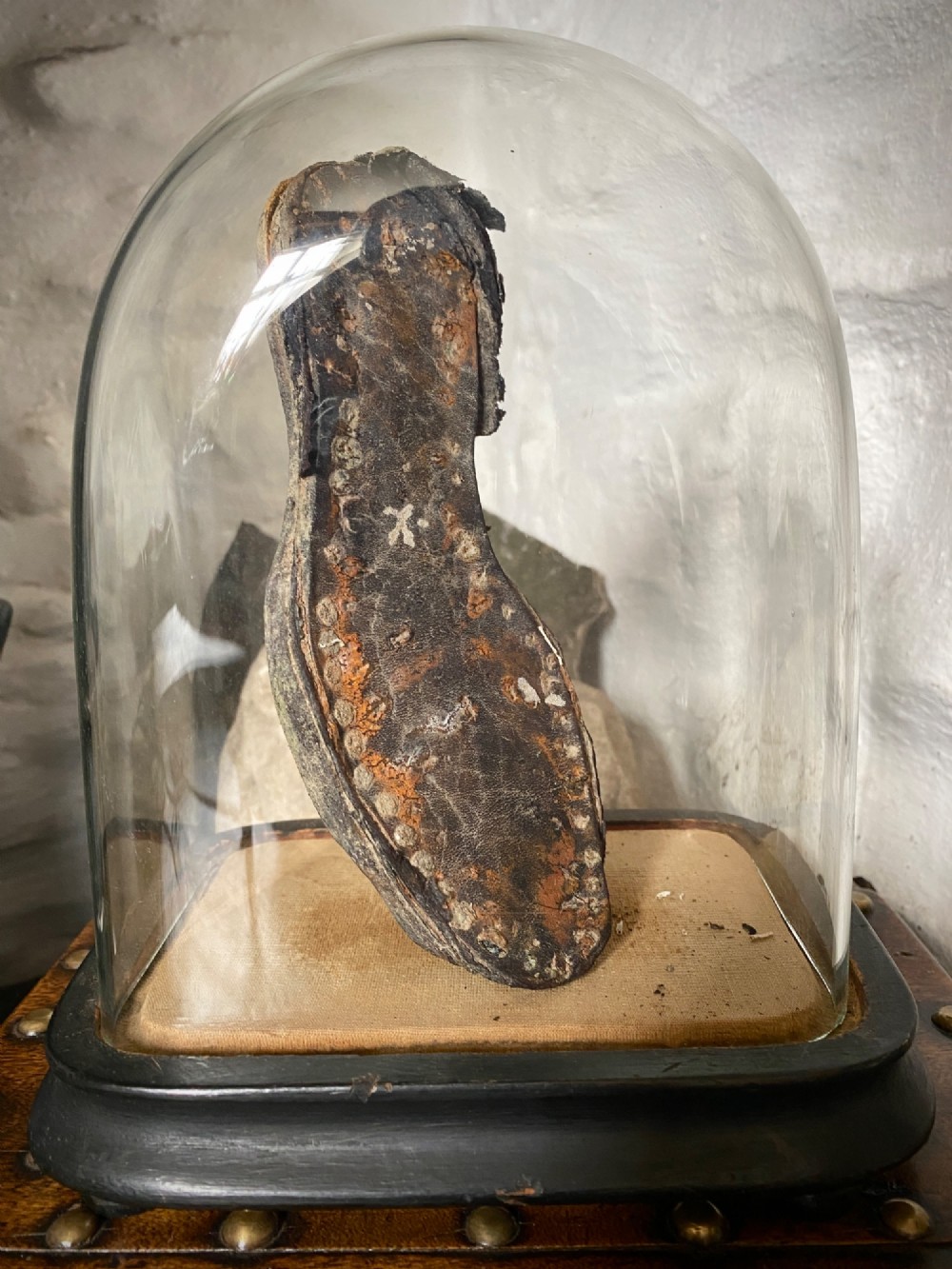 A weathered nineteenth-century leather childs shoe sole mounted upright inside a glass display dome with an ebonised wooden base. View VIII