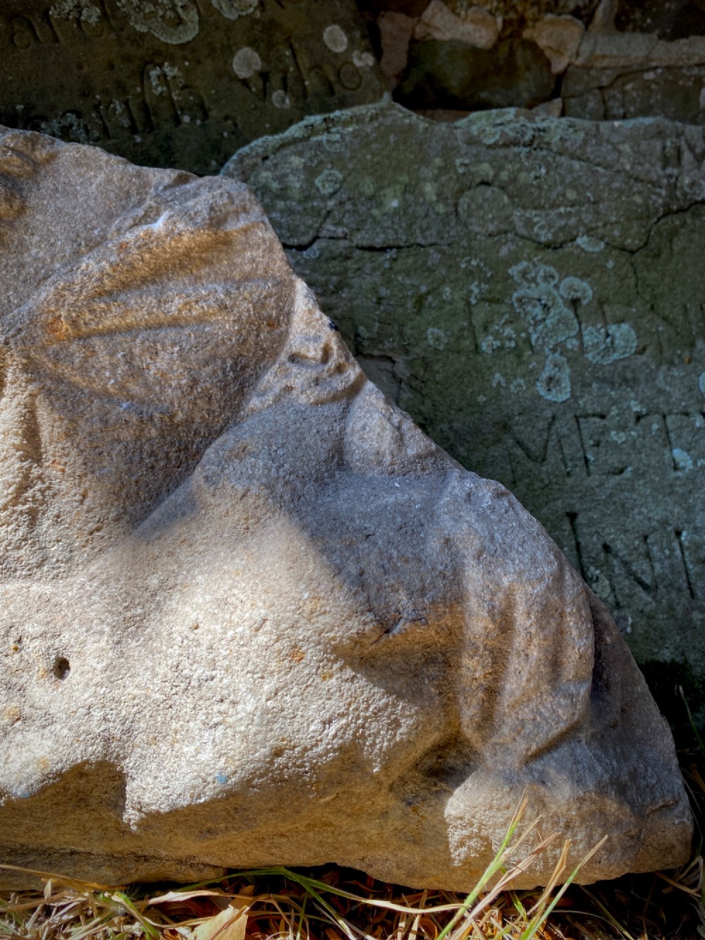 A carved weathered stone fragment depicting a high-relief figure of a winged cherub above a reclining form. View IV