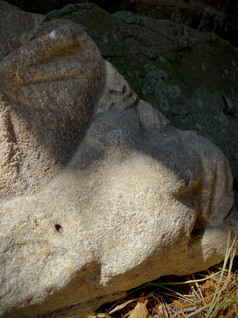 A carved weathered stone fragment depicting a high-relief figure of a winged cherub above a reclining form. View V