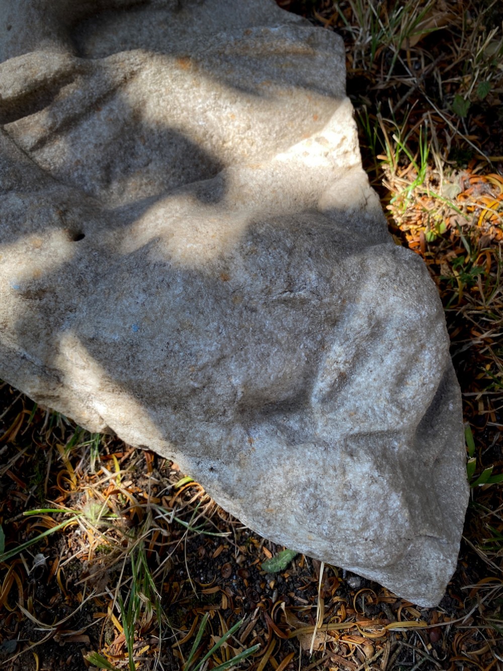 A carved weathered stone fragment depicting a high-relief figure of a winged cherub above a reclining form. View VIII