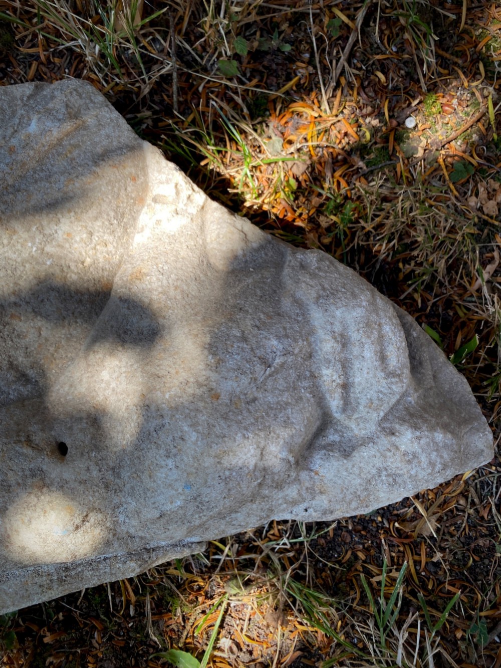 A carved weathered stone fragment depicting a high-relief figure of a winged cherub above a reclining form. View IX
