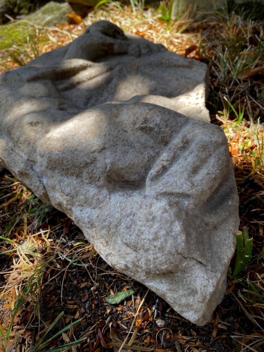 A carved weathered stone fragment depicting a high-relief figure of a winged cherub above a reclining form. View XIII
