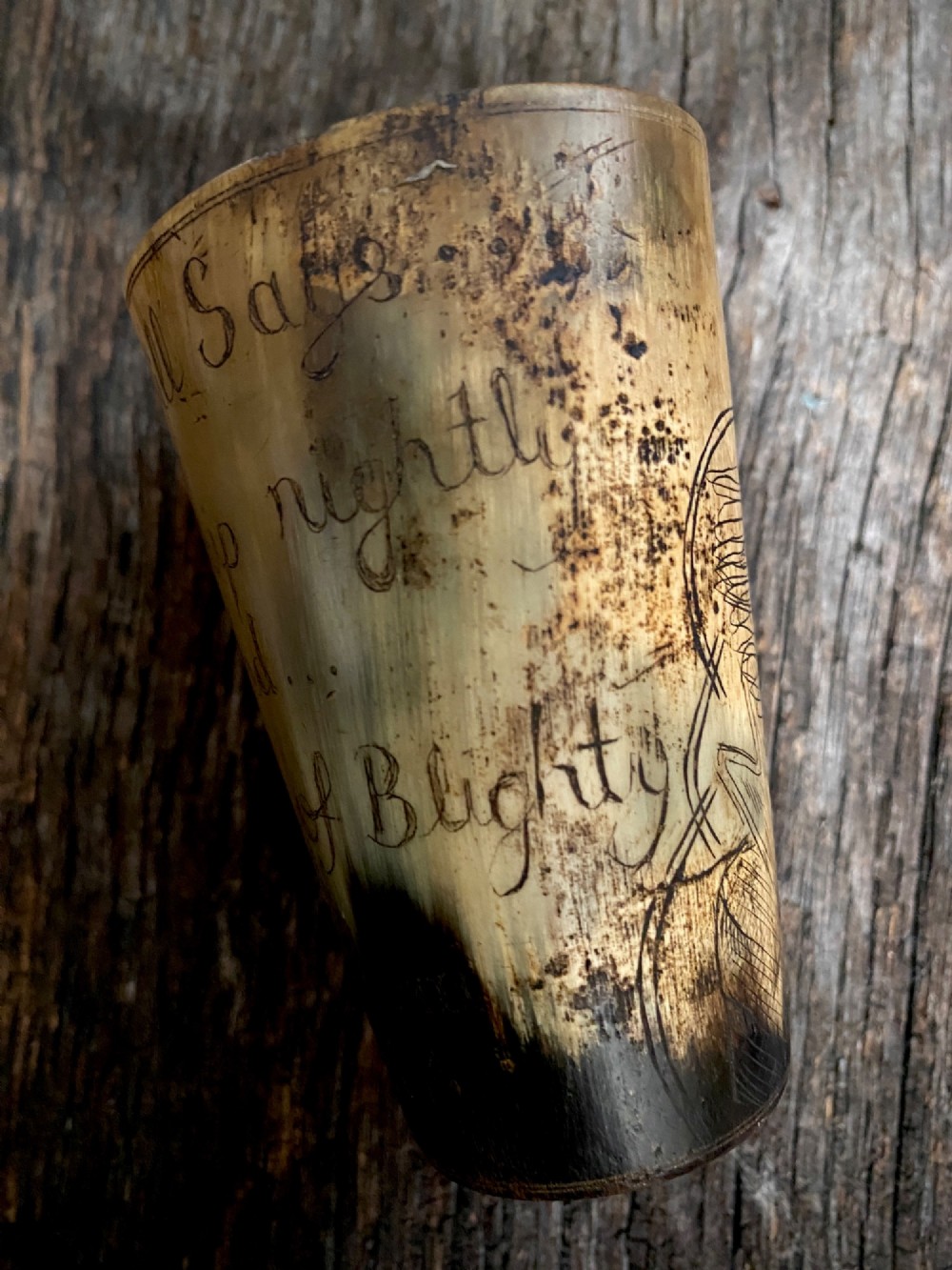 A translucent natural horn beaker featuring a detailed line engraving of the Bruce Bairnsfather character Old Bill wearing a helmet. View III