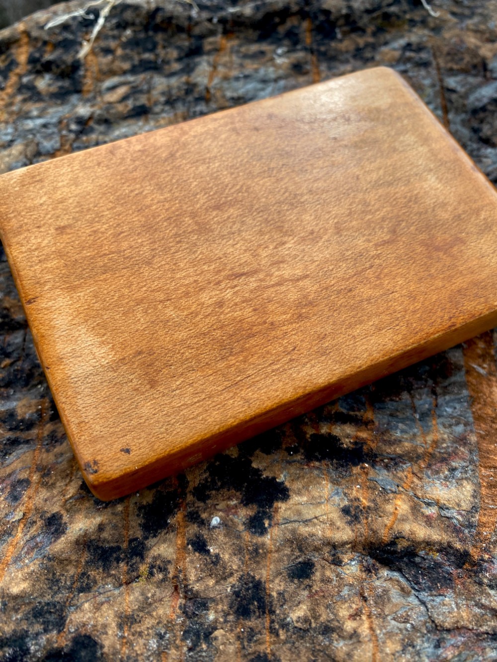 A rectangular carved wooden box lid depicting a uniformed military figure with a detector alongside hand-incised lettering detailing UK locations and dates. View VI