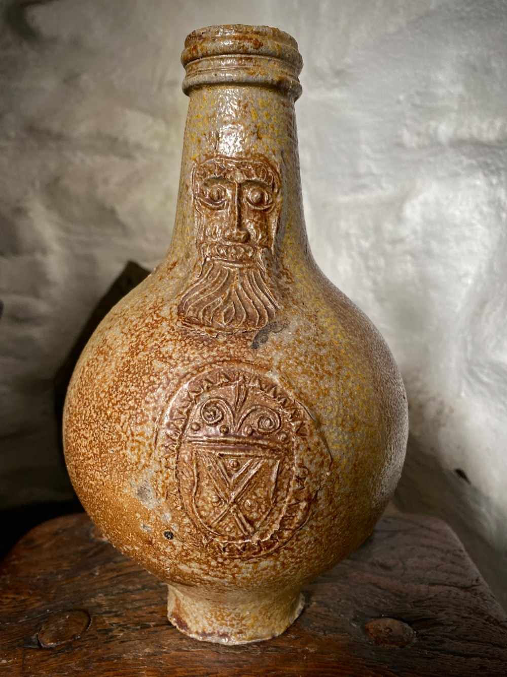 A salt-glazed stoneware Bartmann jug featuring a moulded bearded face mask on the neck and a round medallion crest on the globular body. View III
