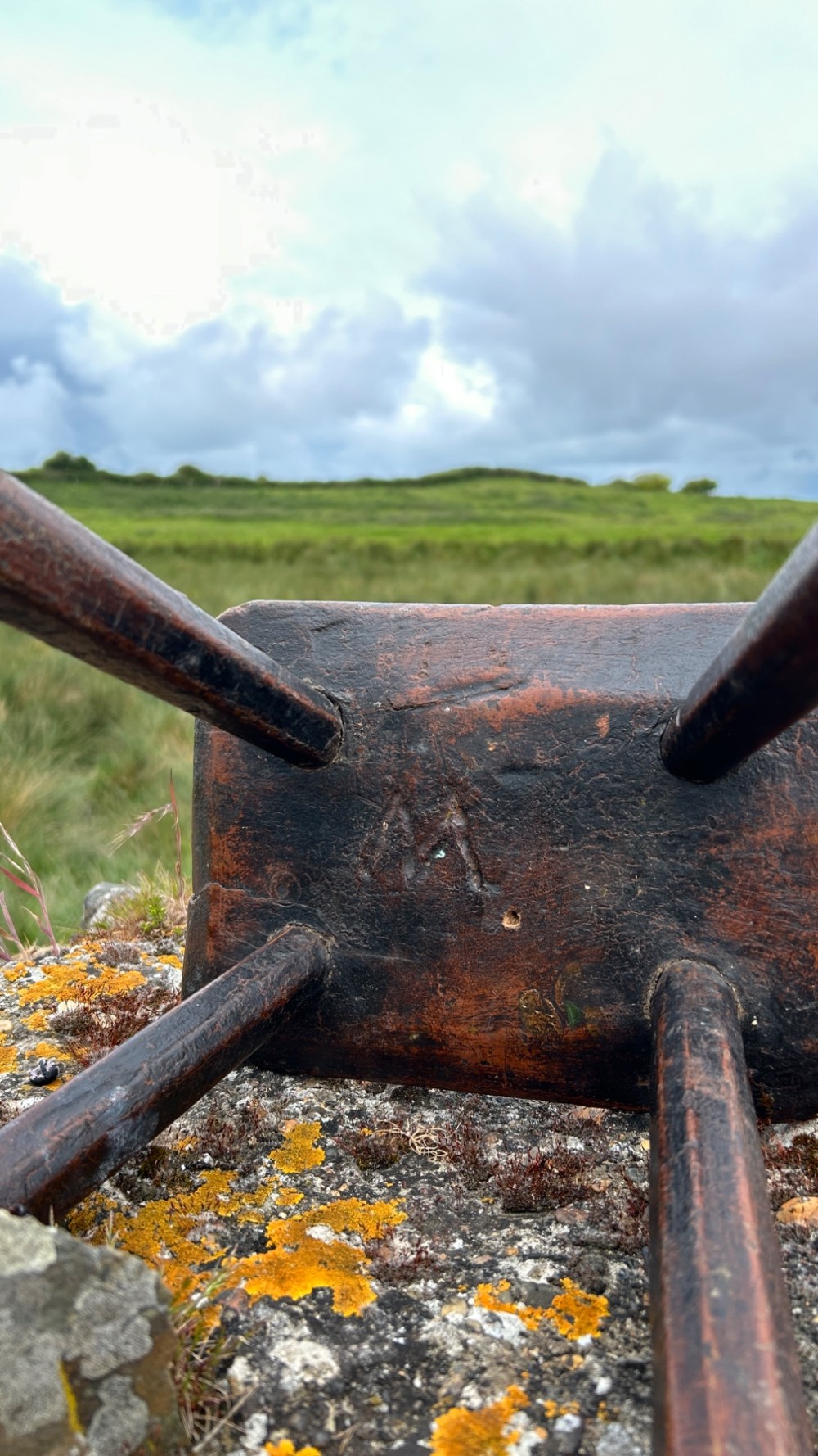 A low rectangular wooden hearth stool featuring dark aged oak timber, four splayed legs, and exposed wedged tenon joints on the top surface. View IV