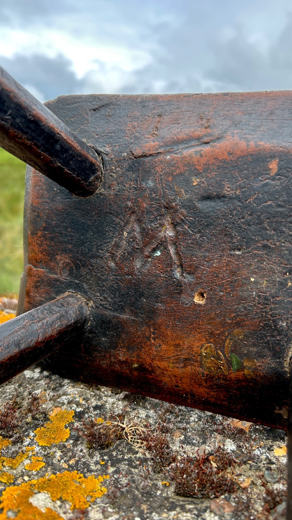 A low rectangular wooden hearth stool featuring dark aged oak timber, four splayed legs, and exposed wedged tenon joints on the top surface. View VI