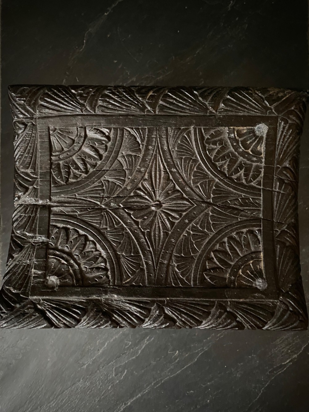 A dark brown carved oak stool featuring hand-carved shell motif decoration on the top seat and four turned wooden legs. View III