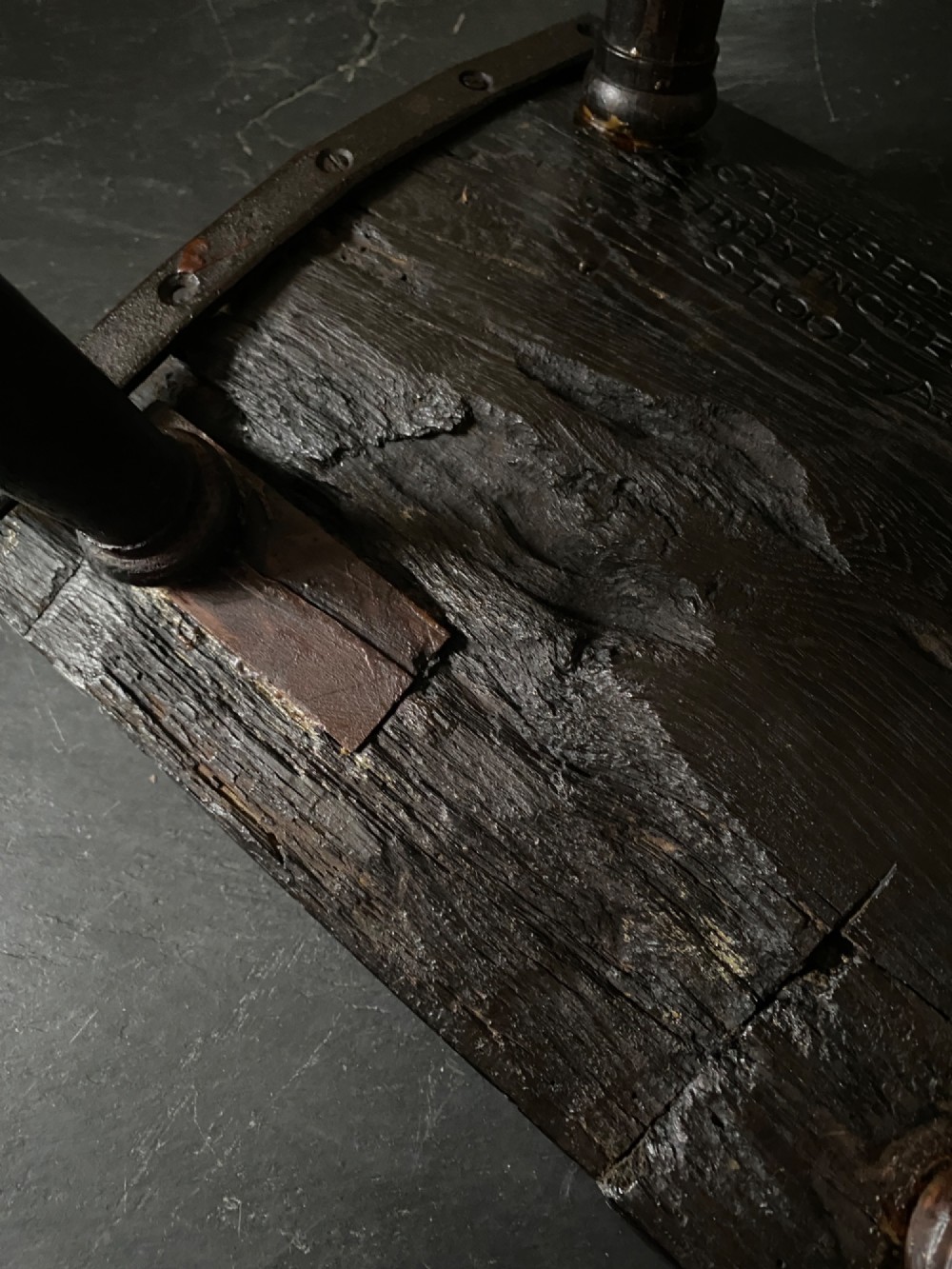A dark brown carved oak stool featuring hand-carved shell motif decoration on the top seat and four turned wooden legs. View VIII
