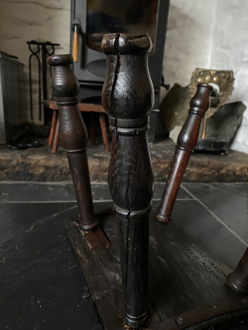 A dark brown carved oak stool featuring hand-carved shell motif decoration on the top seat and four turned wooden legs. View IX