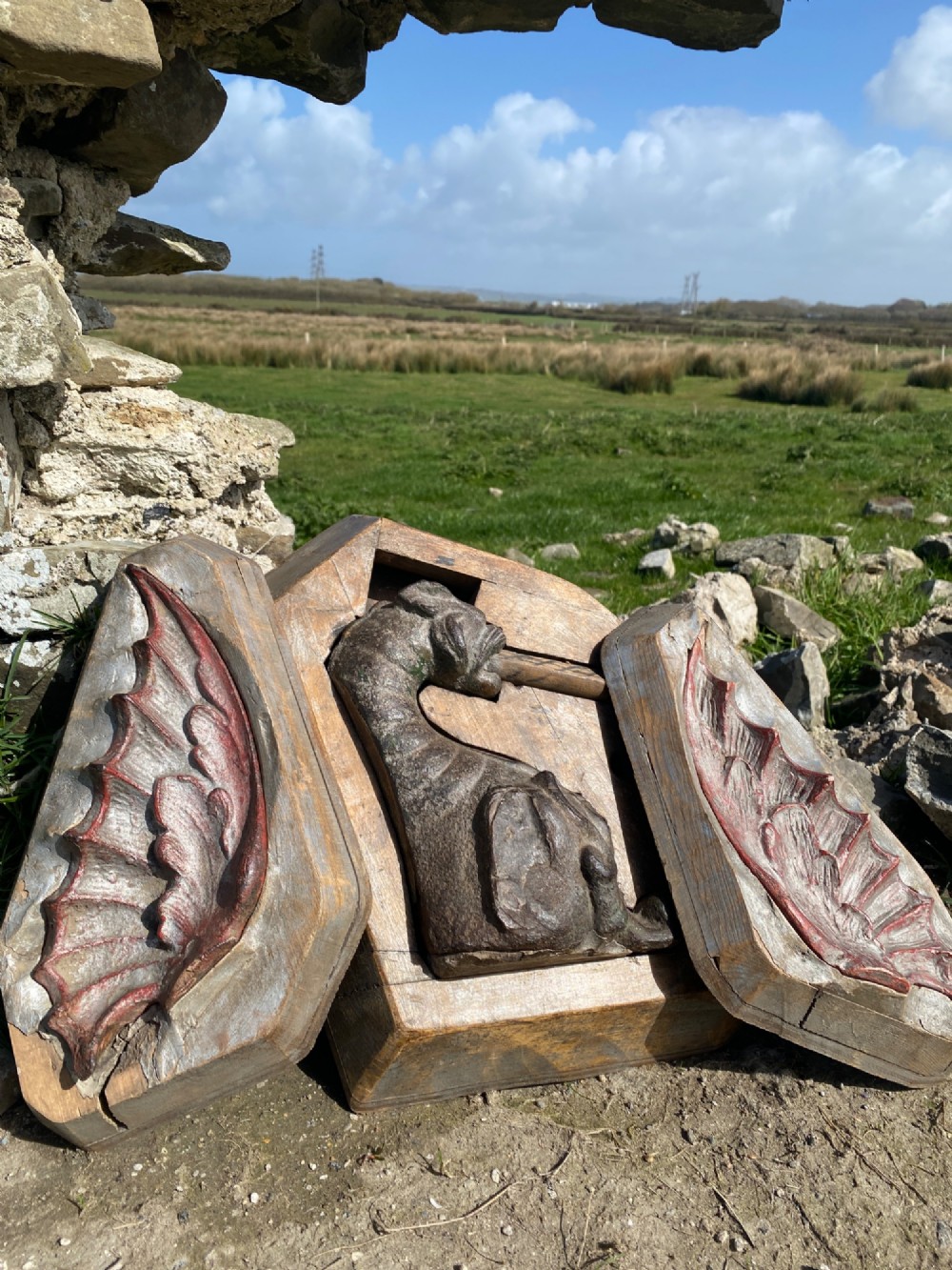 A three-piece set of carved wooden pattern moulds featuring a central seated gargoyle figure flanked by two bat-like wing panels with red paint accents.