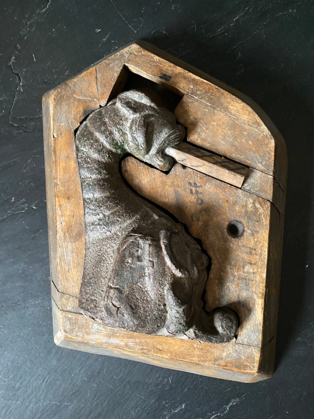A three-piece set of carved wooden pattern moulds featuring a central seated gargoyle figure flanked by two bat-like wing panels with red paint accents. View II
