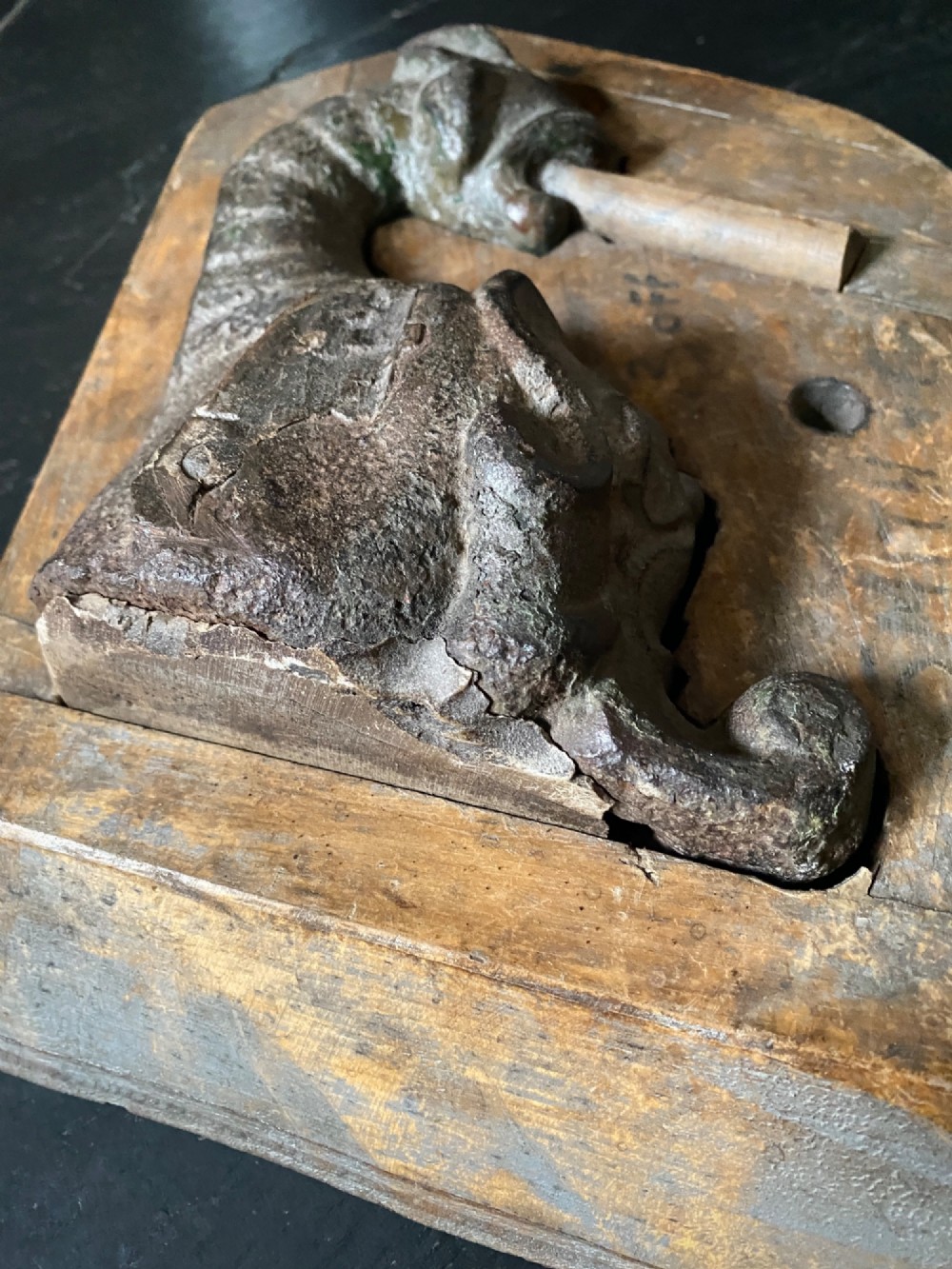 A three-piece set of carved wooden pattern moulds featuring a central seated gargoyle figure flanked by two bat-like wing panels with red paint accents. View III