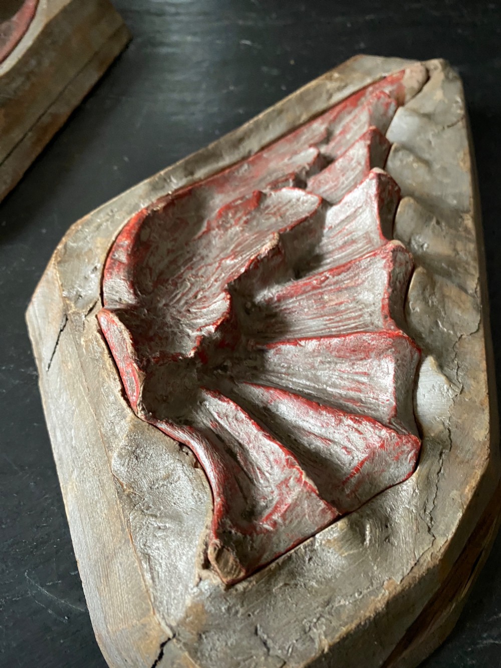 A three-piece set of carved wooden pattern moulds featuring a central seated gargoyle figure flanked by two bat-like wing panels with red paint accents. View VIII