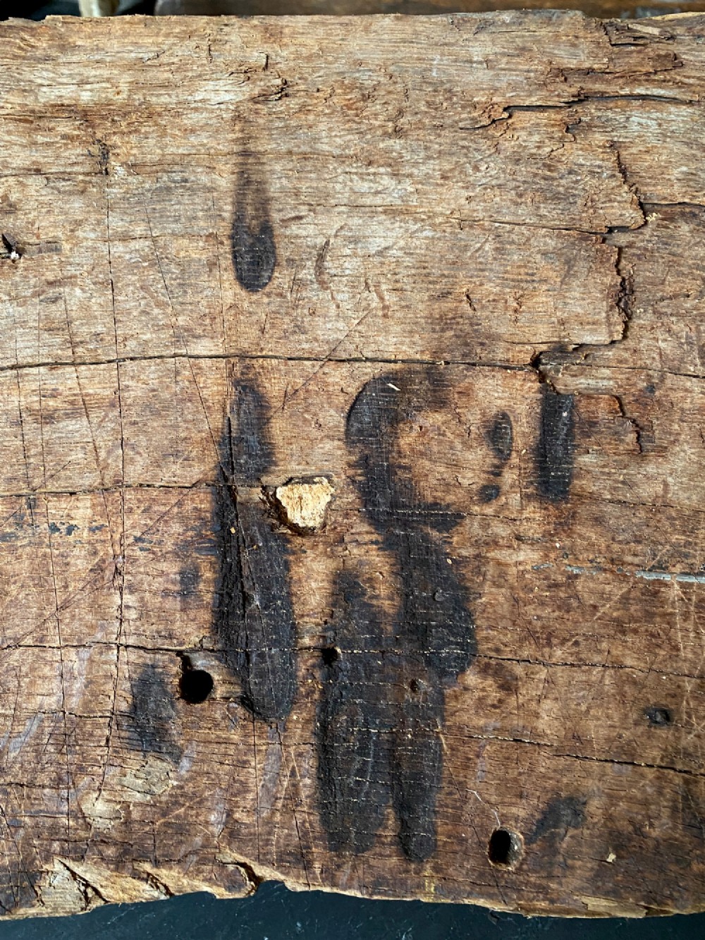 A tall, hand-hewn 17th-century solid oak beam featuring multiple dark apotropaic taper burn marks along its weathered wood surface. View II