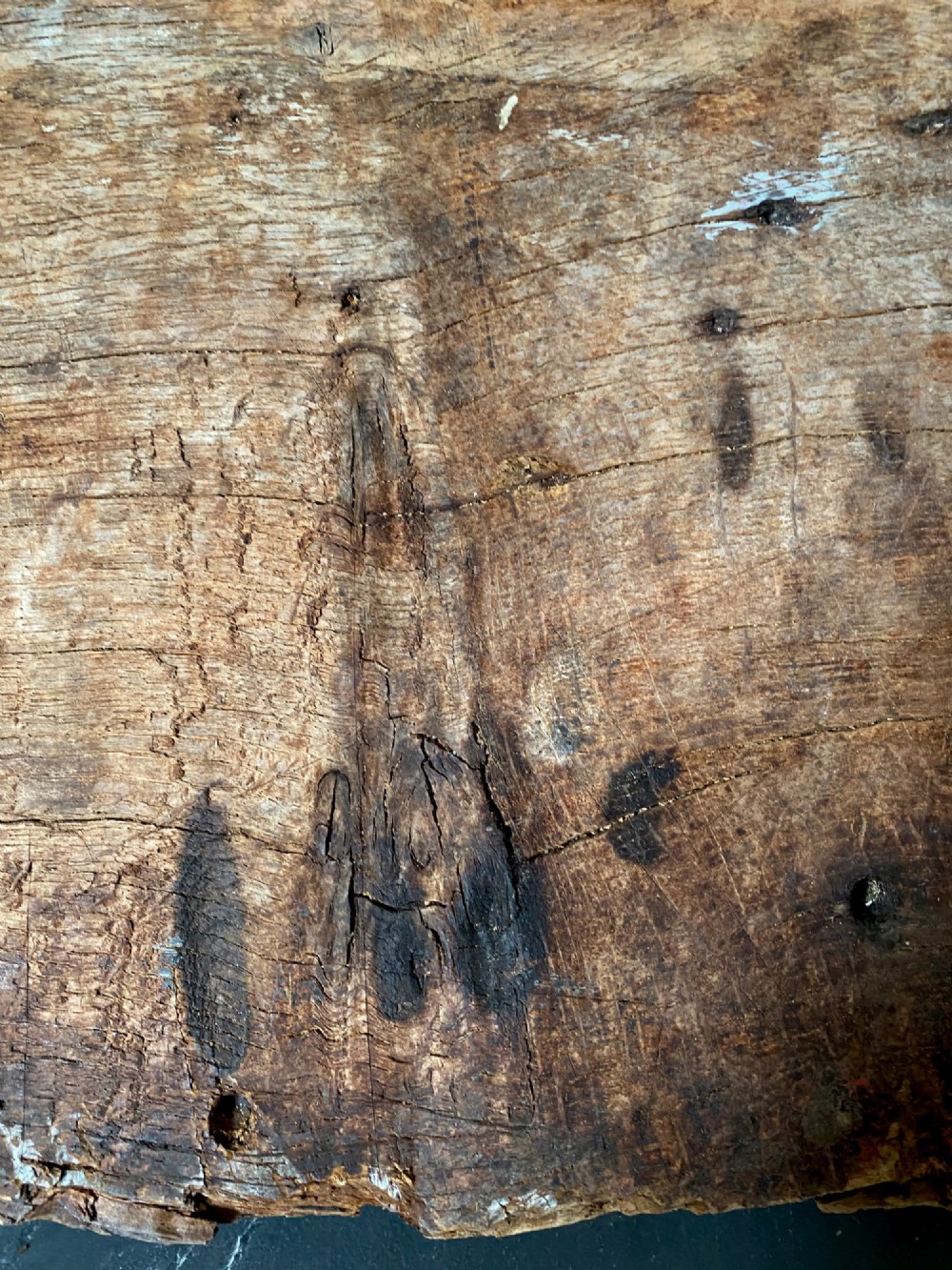 A tall, hand-hewn 17th-century solid oak beam featuring multiple dark apotropaic taper burn marks along its weathered wood surface. View V