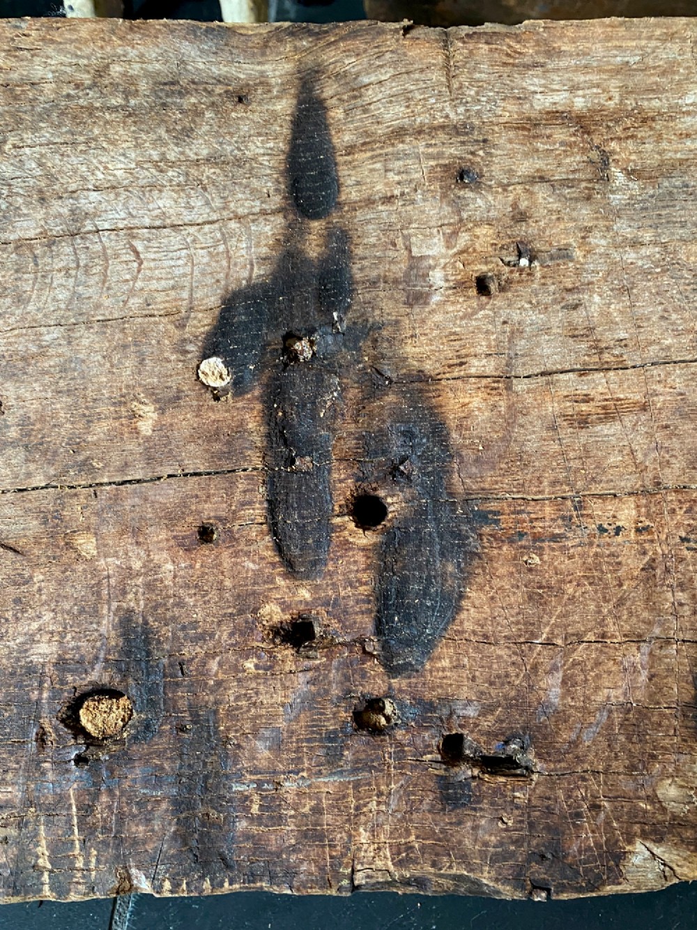 A tall, hand-hewn 17th-century solid oak beam featuring multiple dark apotropaic taper burn marks along its weathered wood surface. View VIII