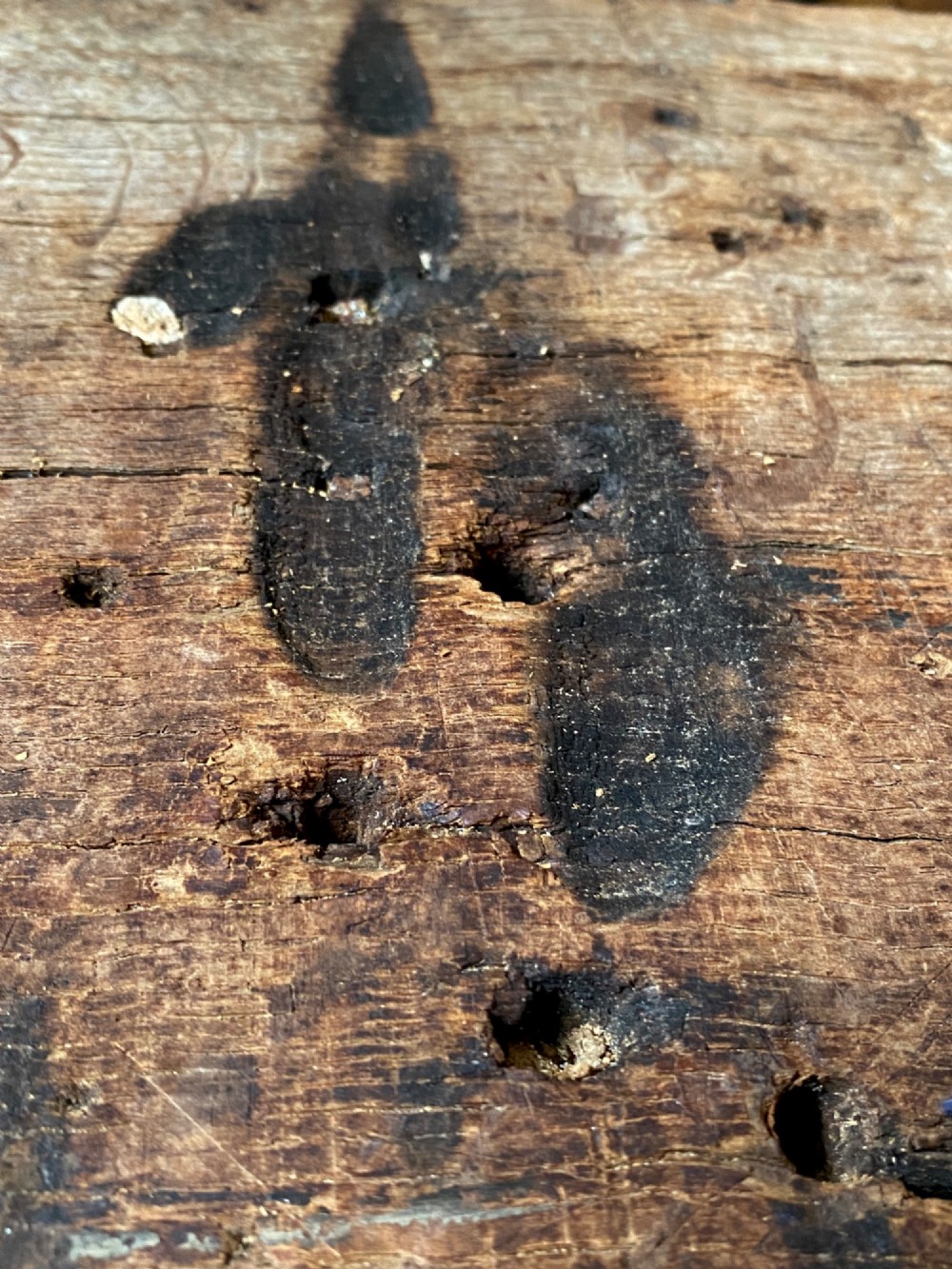 A tall, hand-hewn 17th-century solid oak beam featuring multiple dark apotropaic taper burn marks along its weathered wood surface. View IX