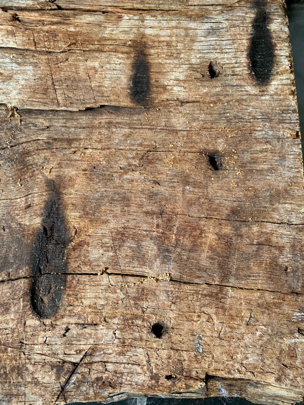A tall, hand-hewn 17th-century solid oak beam featuring multiple dark apotropaic taper burn marks along its weathered wood surface. View X