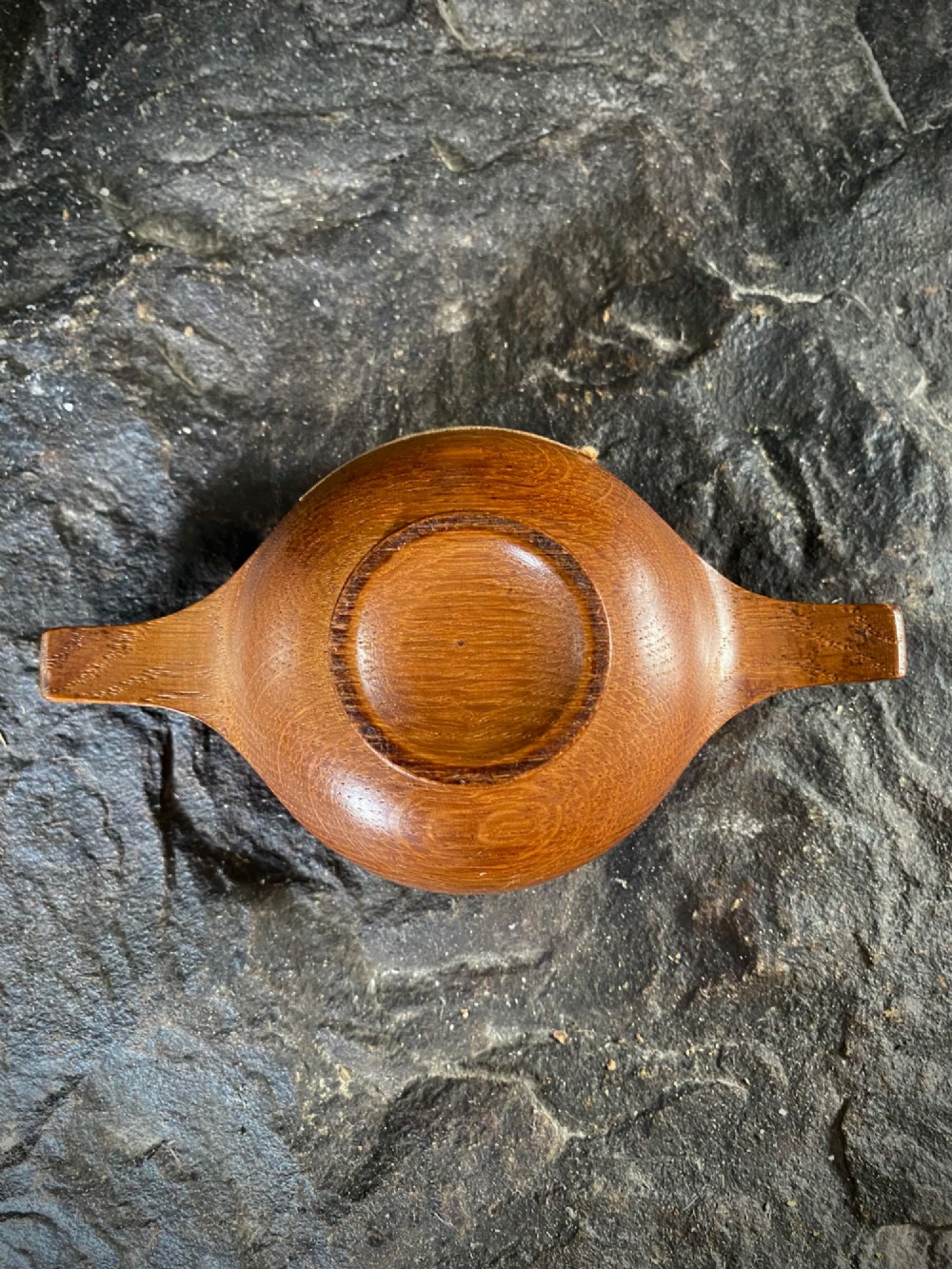 A small carved wooden quaich featuring two side handles and an aged handwritten paper label attached to the front bowl. View IV