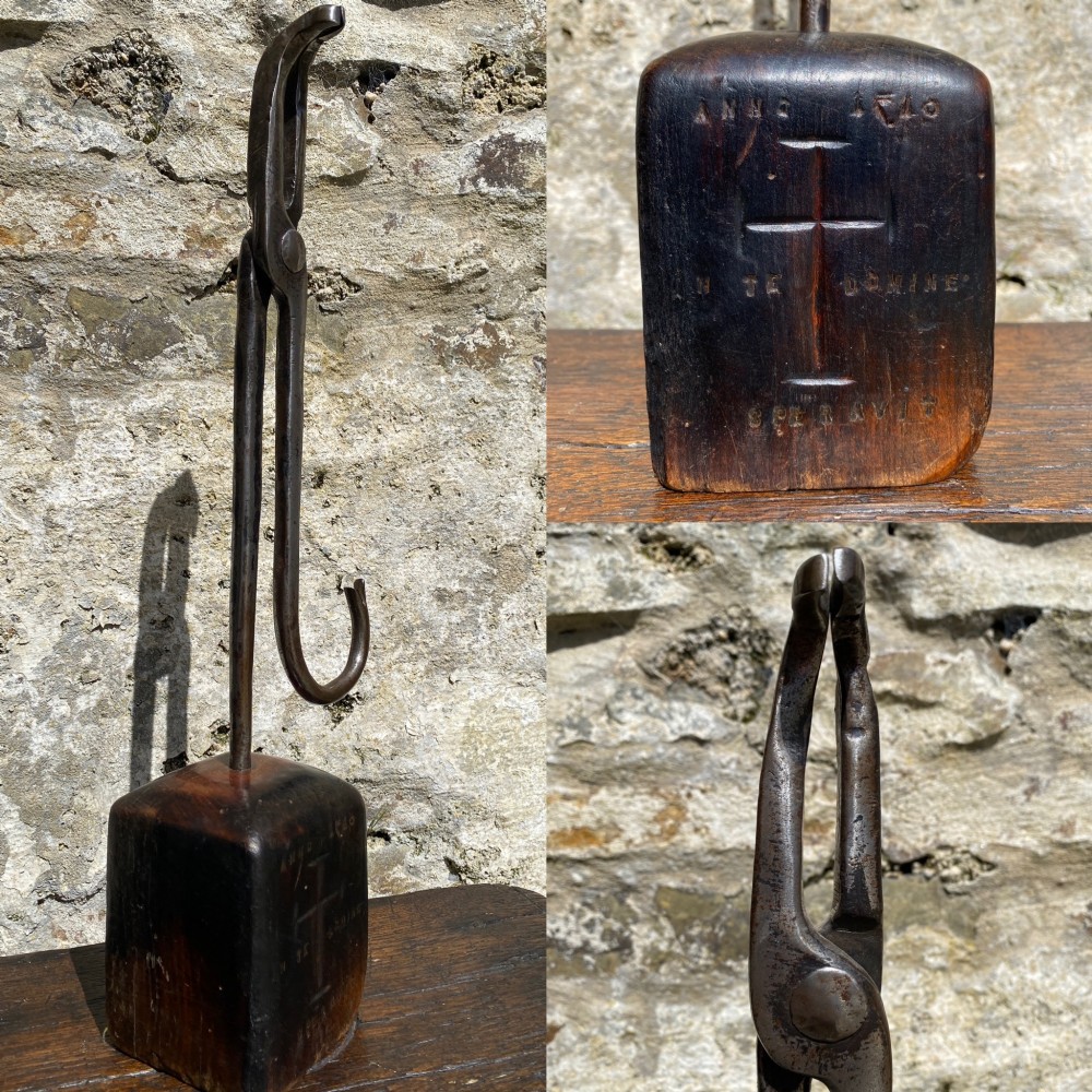 A forged steel tool with an integral lower hook mounted vertically into a square dark wooden block engraved with a cross and text. View II
