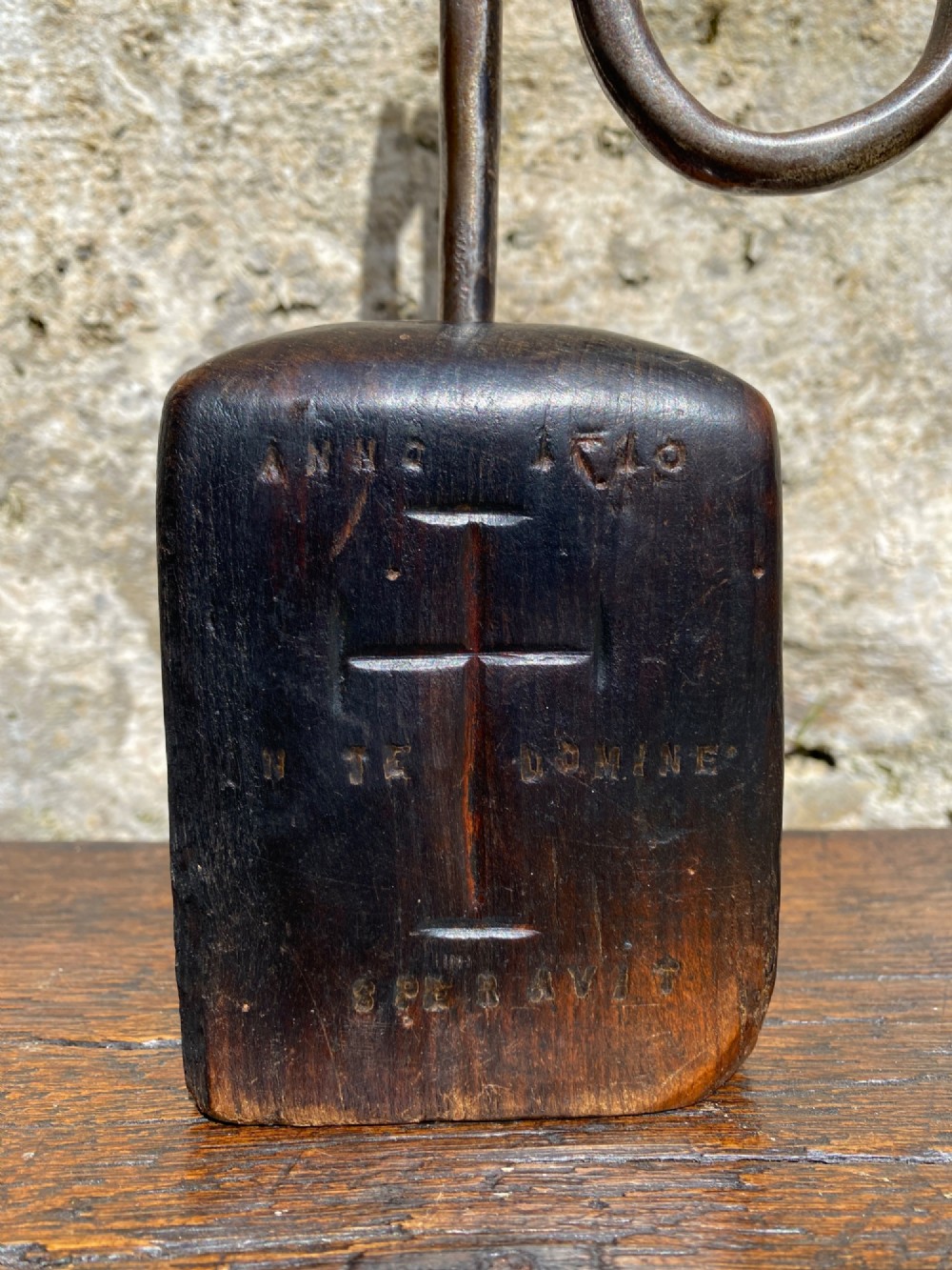 A forged steel tool with an integral lower hook mounted vertically into a square dark wooden block engraved with a cross and text. View III