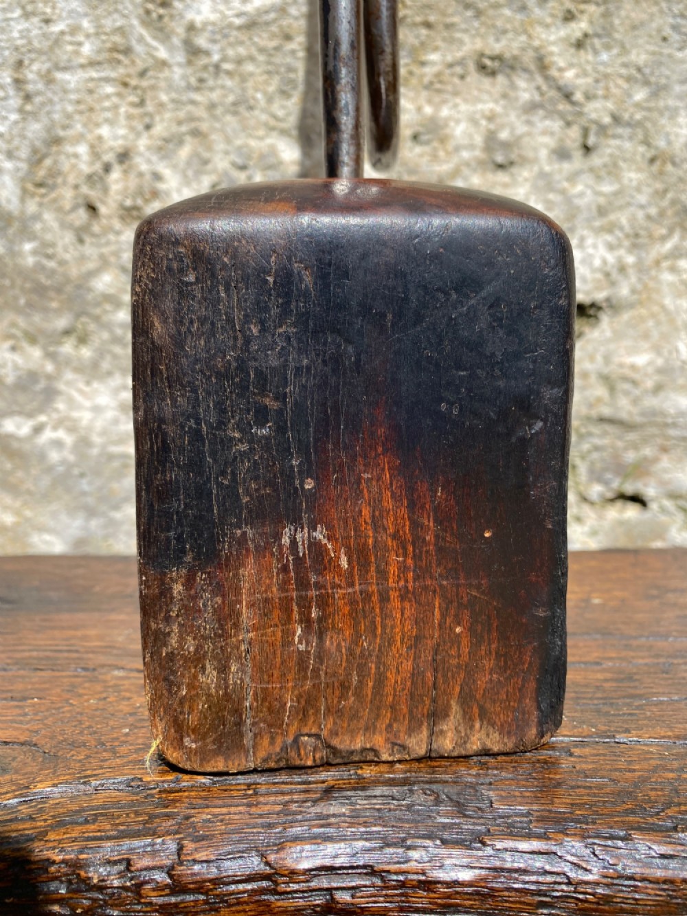 A forged steel tool with an integral lower hook mounted vertically into a square dark wooden block engraved with a cross and text. View VI