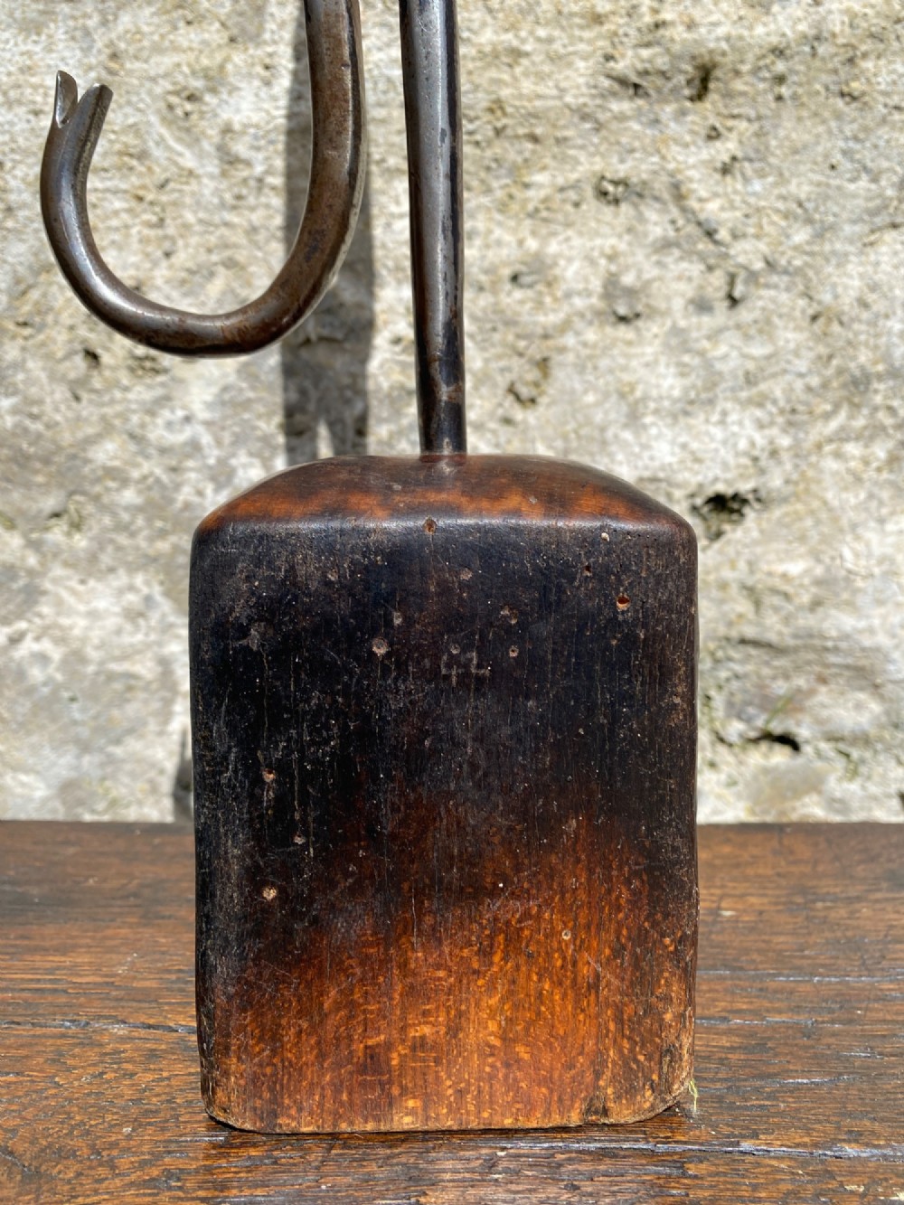 A forged steel tool with an integral lower hook mounted vertically into a square dark wooden block engraved with a cross and text. View VIII