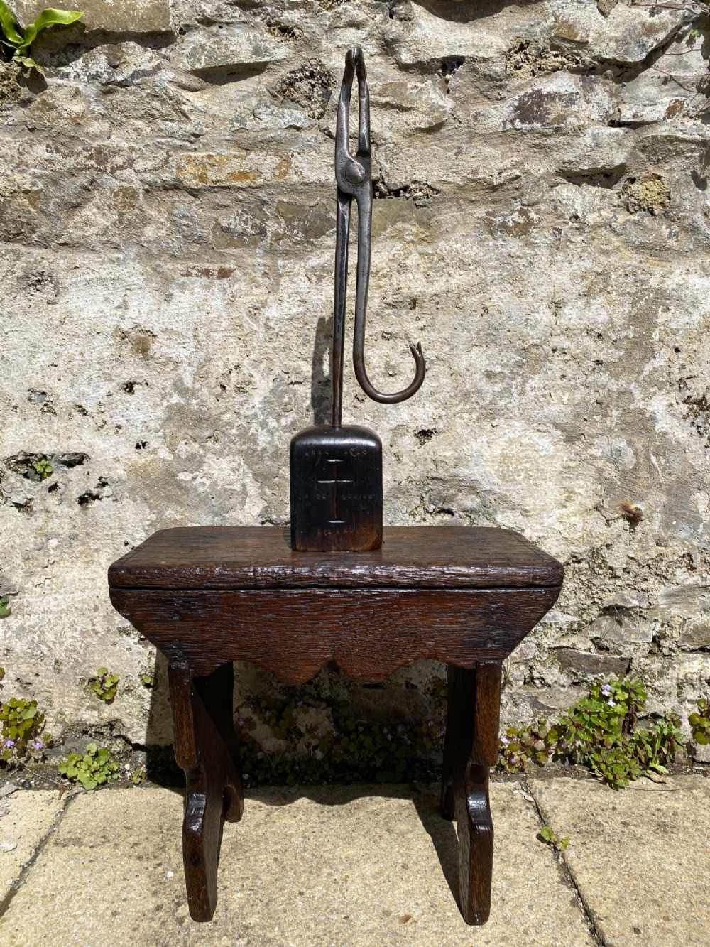 A forged steel tool with an integral lower hook mounted vertically into a square dark wooden block engraved with a cross and text. View XI