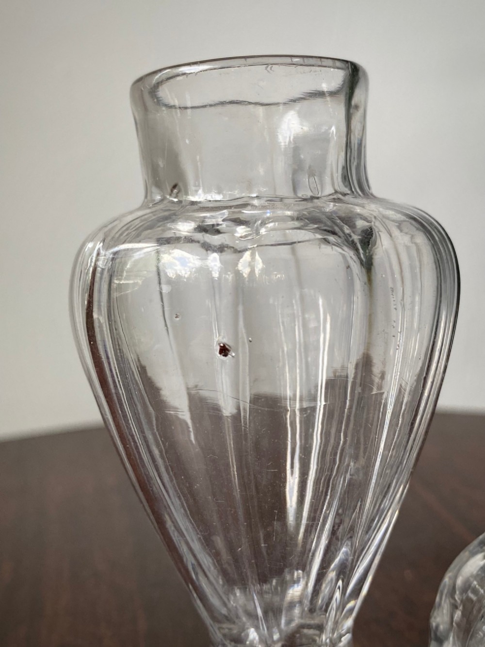 An 18th-century clear hand-blown glass dry mustard jar featuring vertical fluting, a circular footed base, and a removable pointed glass stopper. View VII