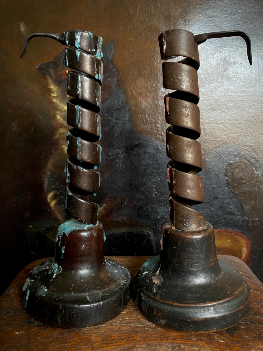 A pair of antique wrought iron spiral candlesticks with hooked handles set into turned dark wood bases. View VI