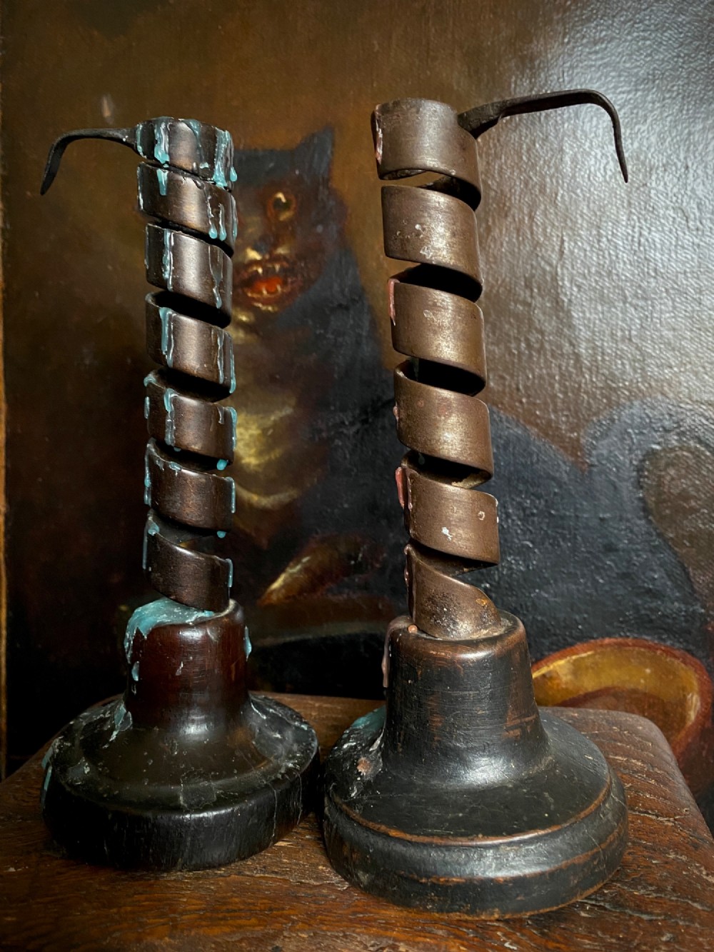 A pair of antique wrought iron spiral candlesticks with hooked handles set into turned dark wood bases. View VIII