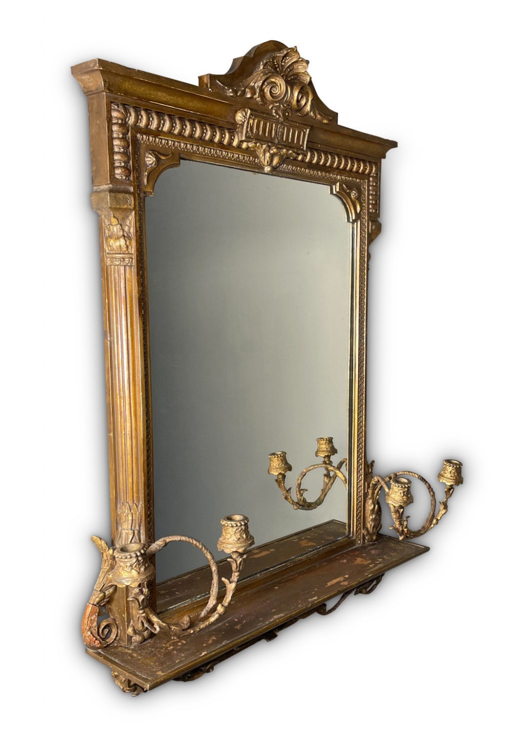 A rectangular giltwood wall mirror featuring a carved crested pediment, fluted side pilasters, a lower shelf, and attached candle sconce arms.