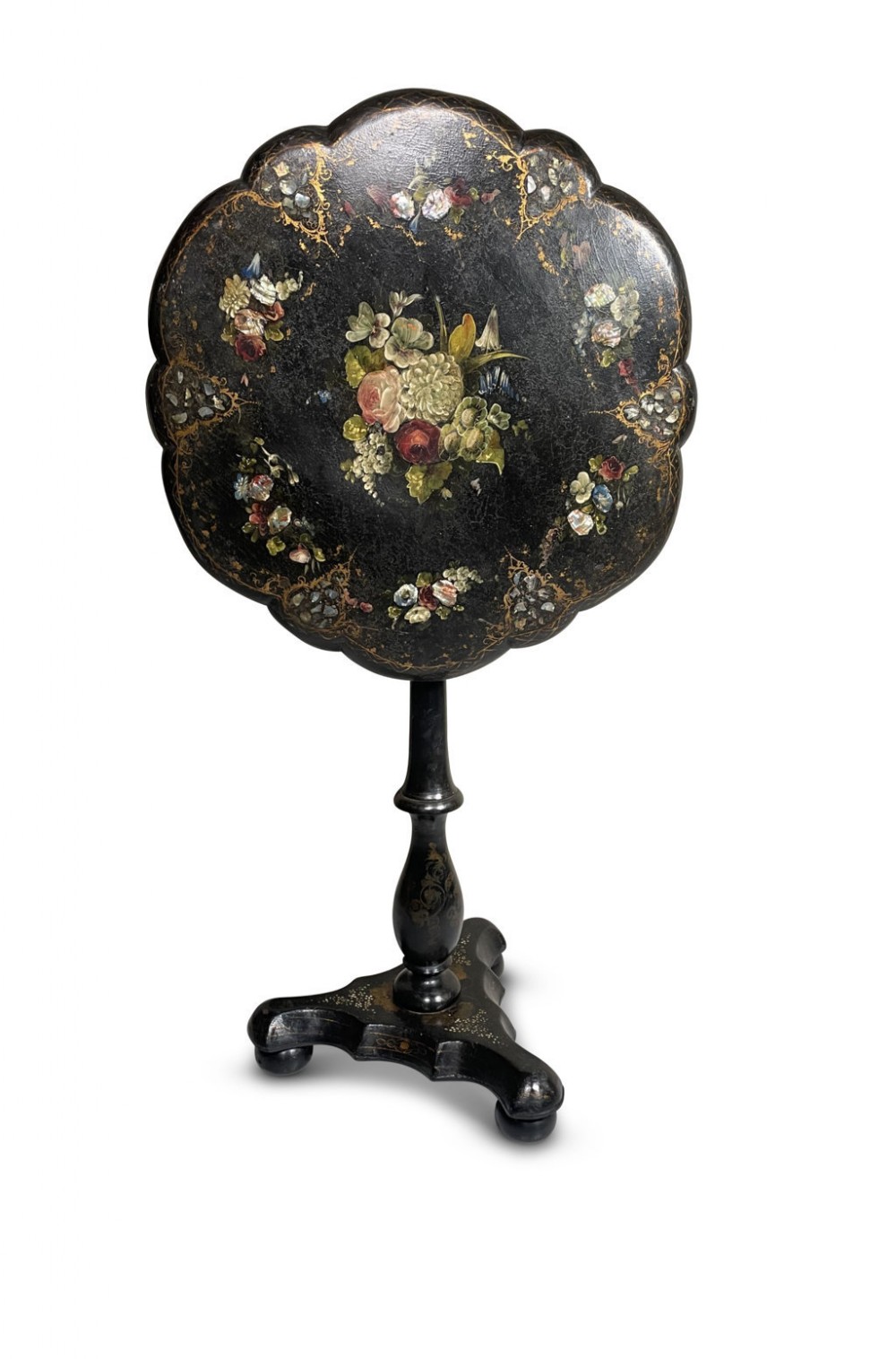 A Victorian ebonised tilt-top table featuring a scalloped rim, hand-painted floral motif, mother-of-pearl inlays, and a central pedestal on tripod feet.