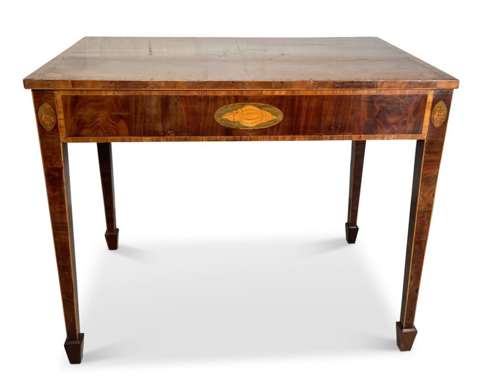 A rectangular Regency mahogany table featuring a central shell motif inlay on the front apron, string crossbanding, and square tapered legs.