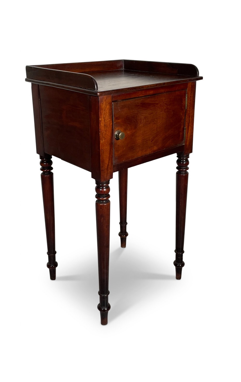 A George III mahogany nightstand featuring a raised tray top, a single cupboard door with a brass knob, and four slender turned legs.