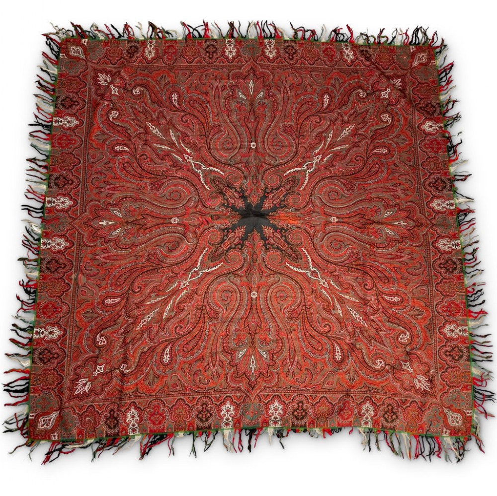 A square Victorian red wool Paisley shawl featuring intricate woven boteh patterns, a dark central star motif, and a multi-coloured fringed border.