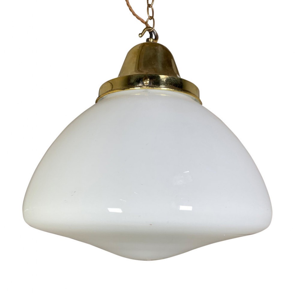 An opaque white glass pendant light shade topped with a brass gallery and suspended from a brass chain.