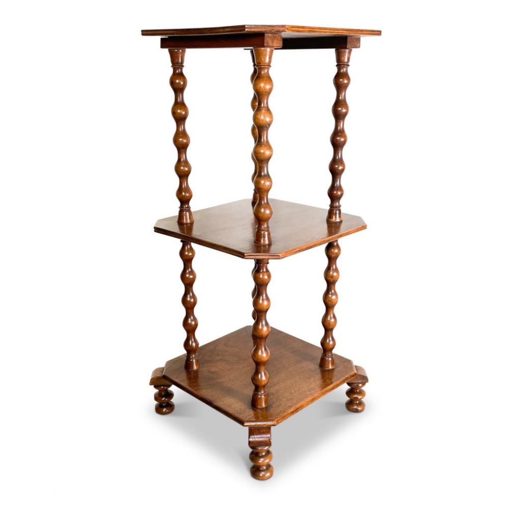 A Victorian three-tiered wooden whatnot featuring bobbin-turned upright columns, canted corners on square shelves, and short turned feet.