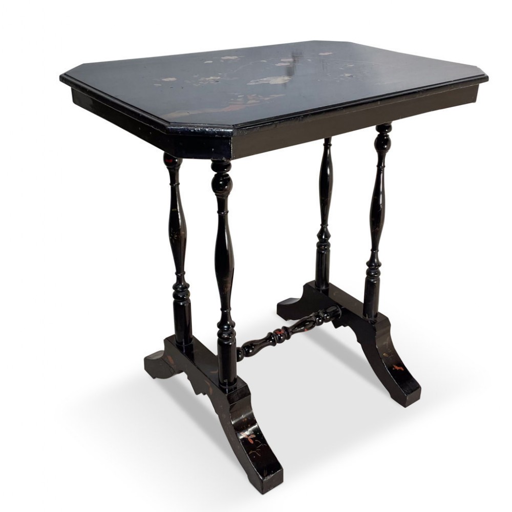 A black lacquered ebonised side table featuring a canted rectangular top decorated with Chinoiserie floral details, supported by slender turned legs and a stretcher base.