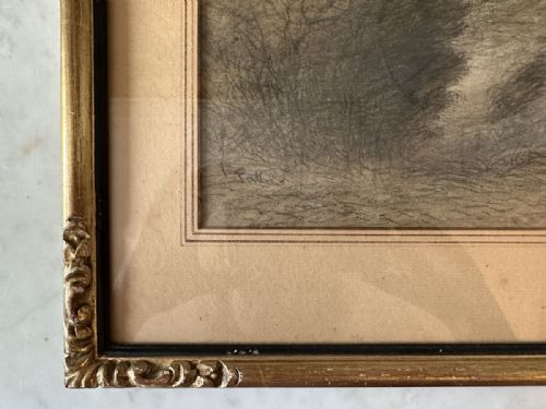 fig 1. An antique monochrome charcoal drawing depicting a dense wooded landscape set within a beige mount and an ornate gilt frame.