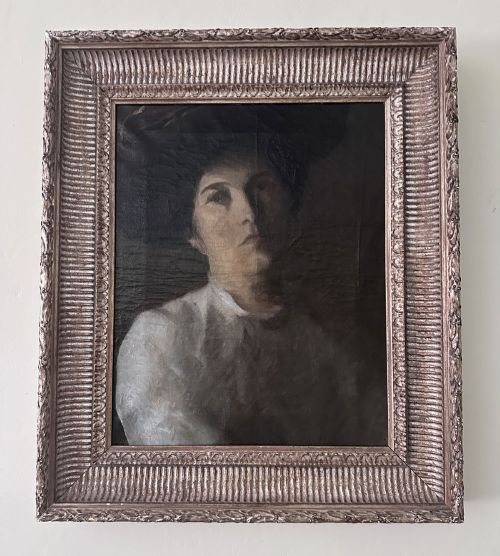 fig 2. An antique oil painting on canvas depicting a woman wearing a dark hat and light-coloured blouse in low-light illumination.