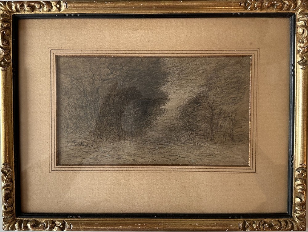 An antique monochrome charcoal drawing depicting a dense wooded landscape set within a beige mount and an ornate gilt frame.