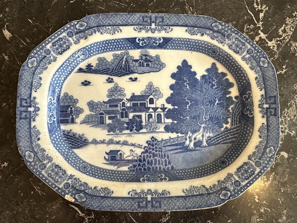 An octagonal blue and white antique transferware meat platter featuring an underglaze Chinoiserie landscape with pagodas, trees, and a river scene.