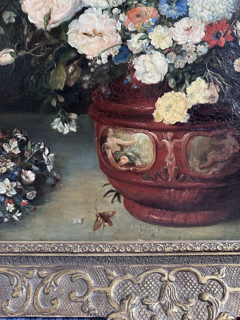 An antique oil painting depicting a dense arrangement of colourful flowers inside a terracotta-toned urn against a dark background. View V